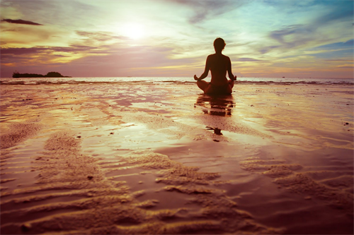 woman mediating at ocean at sunrise